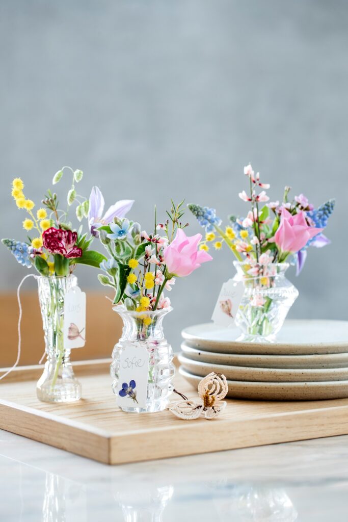 Borddekorasjon til bryllup av små vaser og tilfeldige blomsterbuketter.